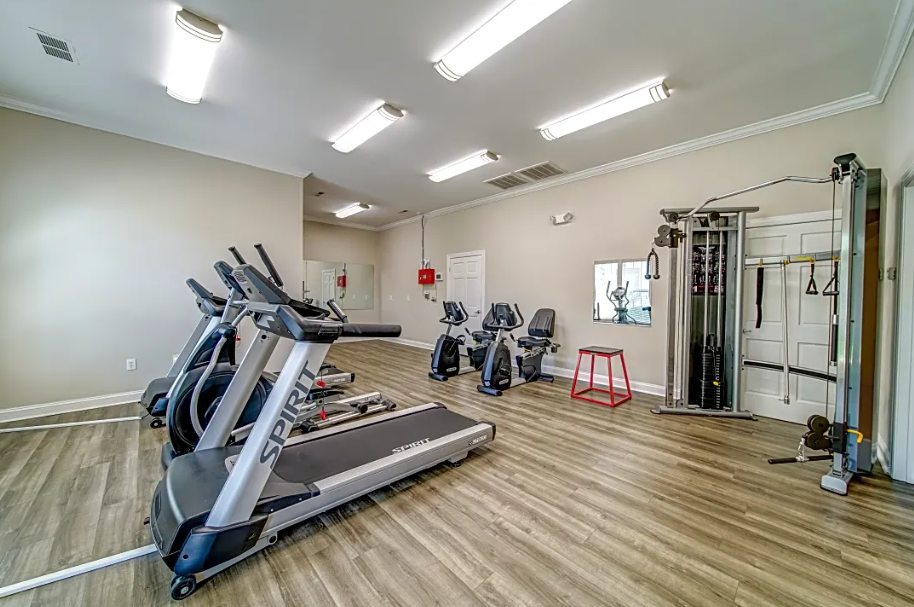 a gym with cardio equipment and weights on a wooden floor