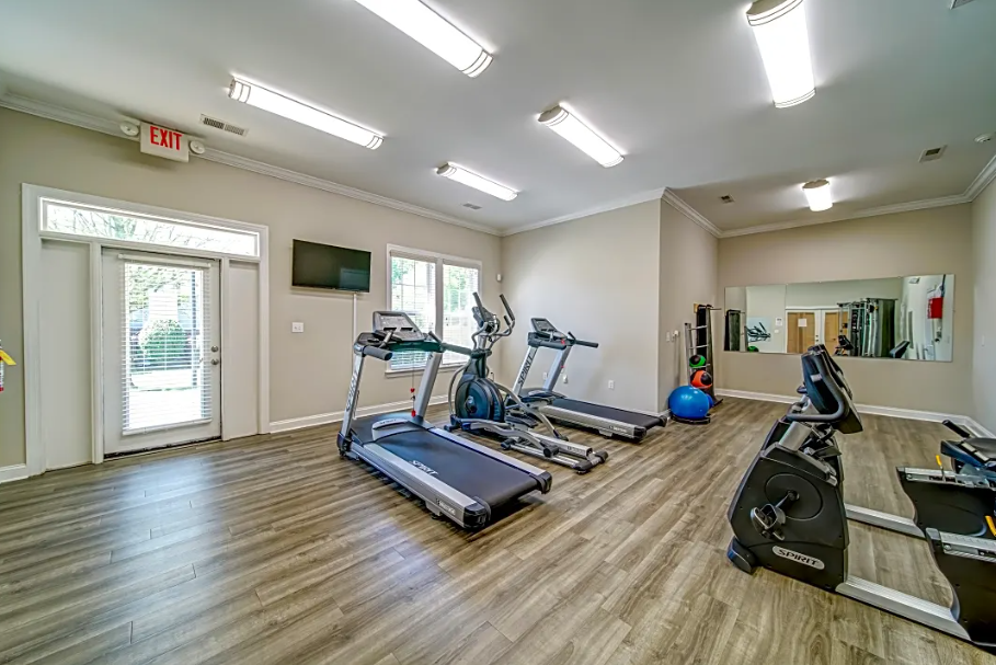 a gym with treadmills and weights and a tv