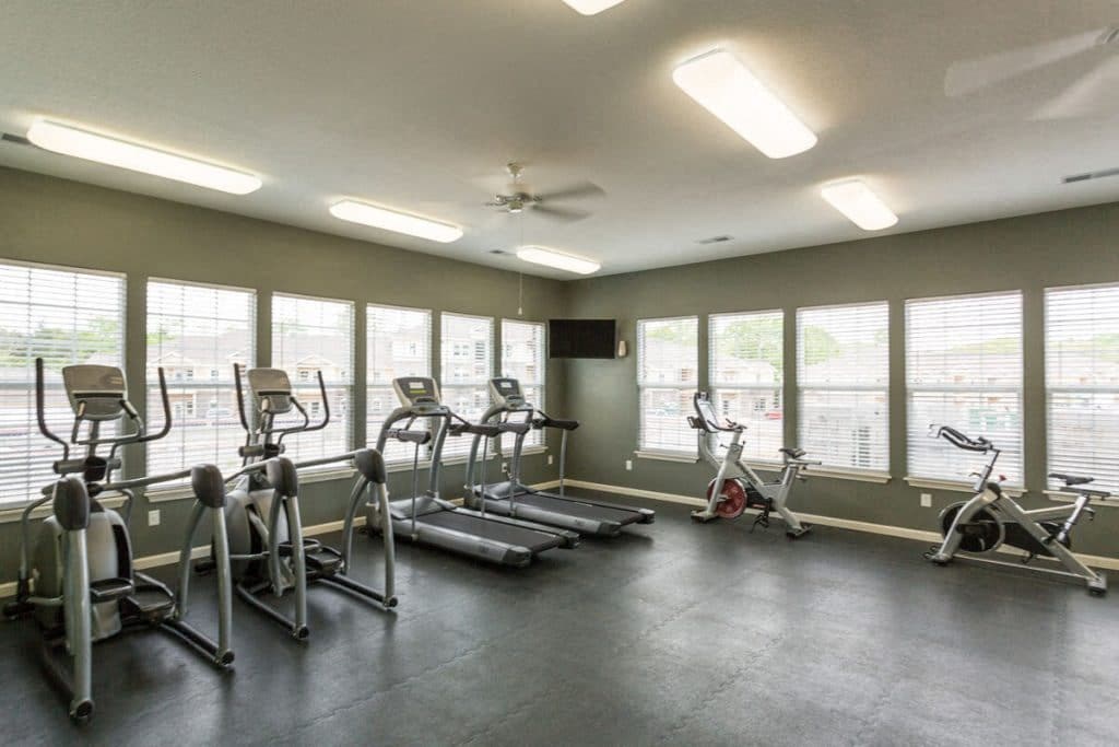 a gym with cardio equipment and windows