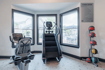A fitness center with a treadmill, exercise balls, and weights.