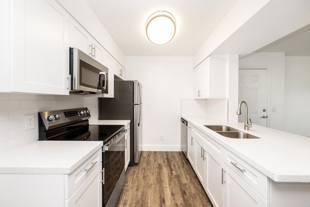 a renovated kitchen with white cabinets and stainless steel appliances