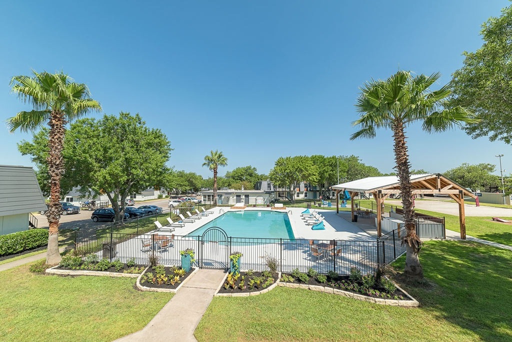 a resort style swimming pool with palm trees and a fence
