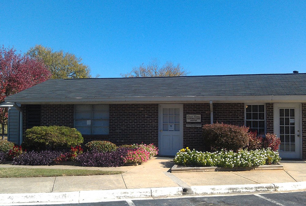 a building with a gray roof and colorful flowers in front of it