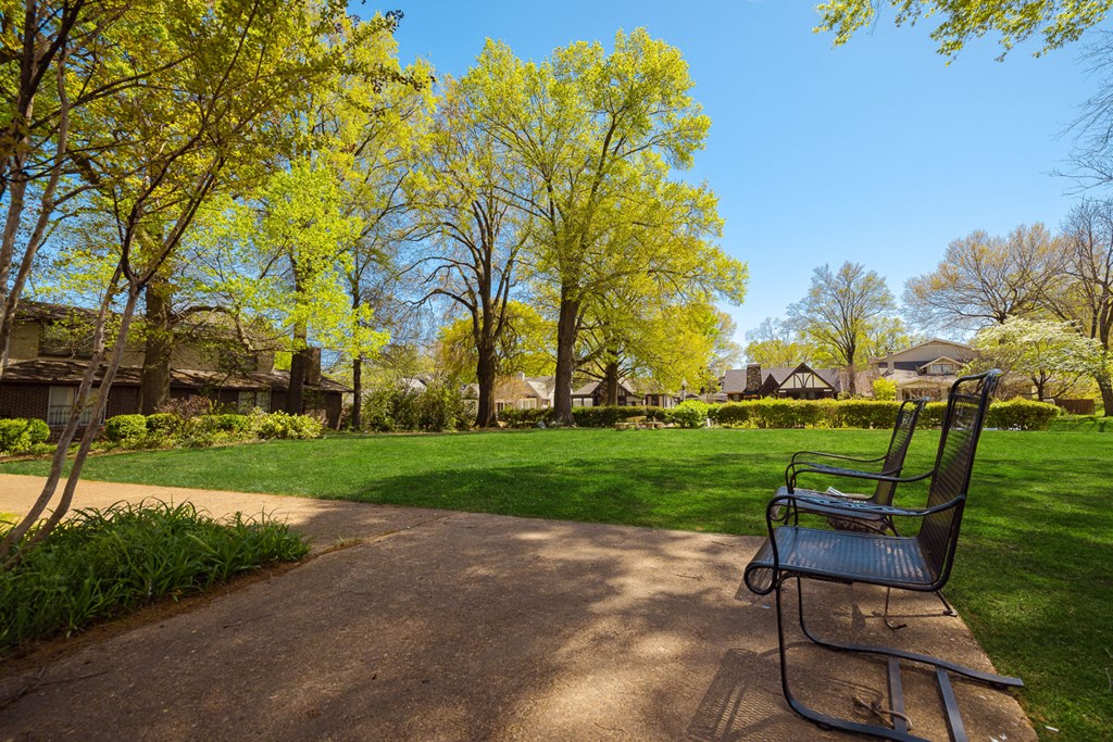 a park bench in front of a grassy area with houses in the background