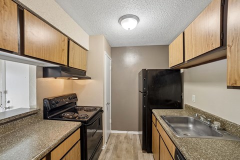A kitchen with a black refrigerator and a black stove top oven.