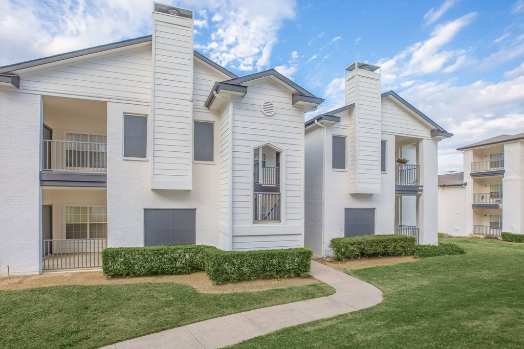 a white apartment building with a sidewalk in front of it
