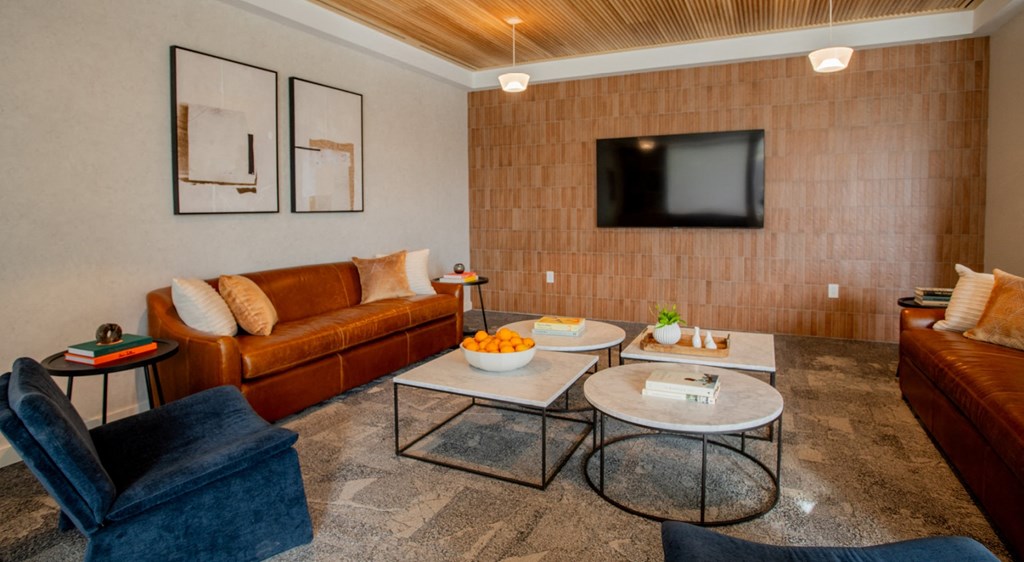 A living room with a brown couch, a blue chair, and a television mounted on the wall.