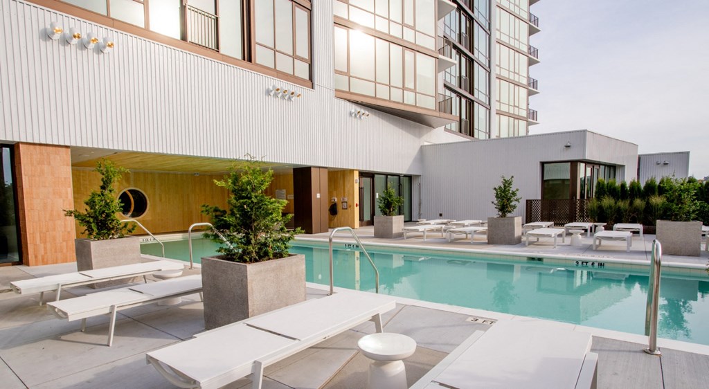 A modern building with a pool and lounge chairs.
