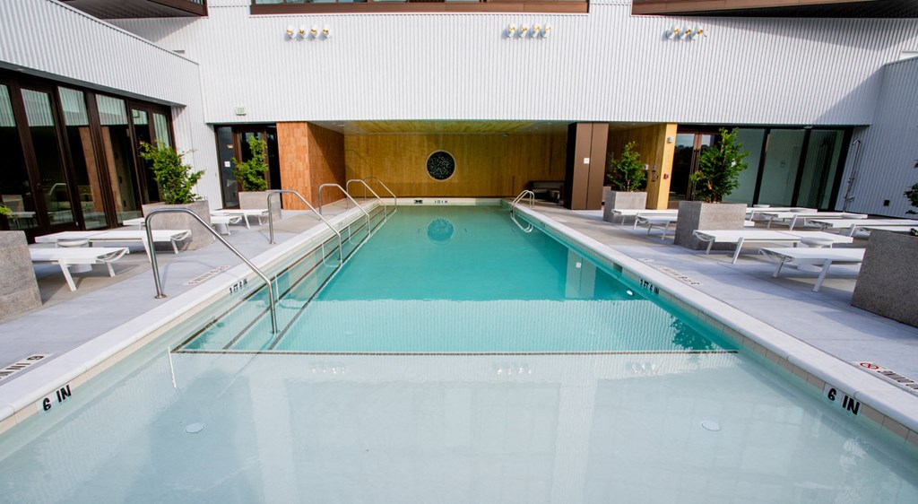 A large indoor swimming pool with lounge chairs on the side.