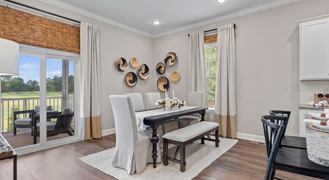 A dining room with a table set for two and a view of the backyard.