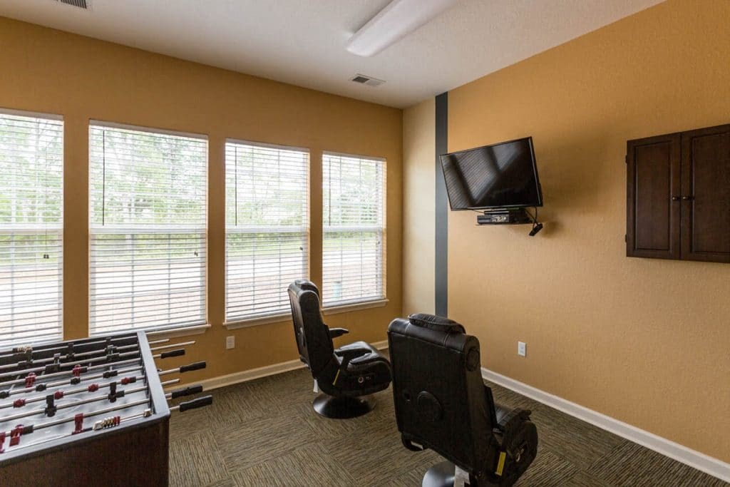 a living room with two chairs and a table with a tv