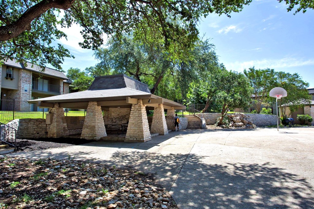 a stone gazebo with a basketball hoop in a courtyard