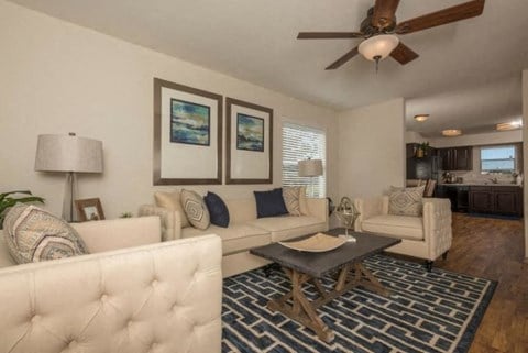 a living room with white furniture and a ceiling fan