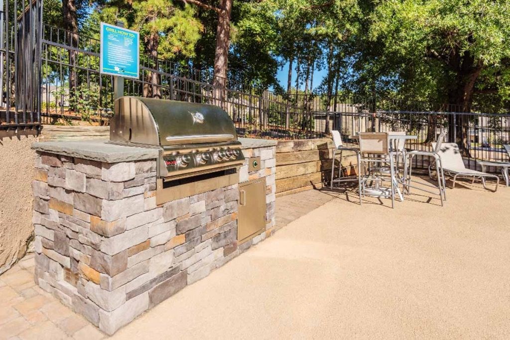 a barbecue grill in a park with tables and chairs