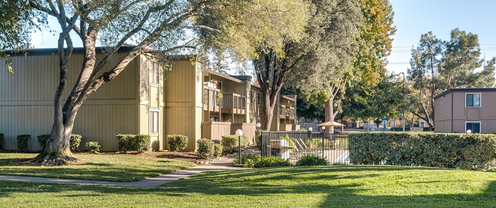 an apartment building with trees and a sidewalk