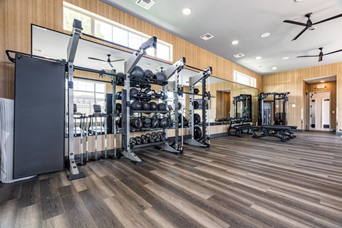 A spacious gym with a variety of equipment and a ceiling fan.