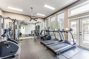 A spacious gym with treadmills, weights, and a fan.