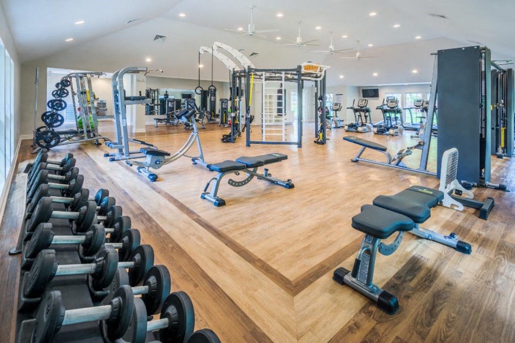 a gym with cardio equipment and weights on the floor