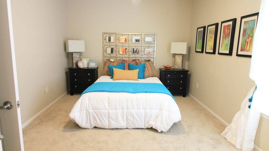 A bedroom with a bed, two nightstands, and pictures on the wall.