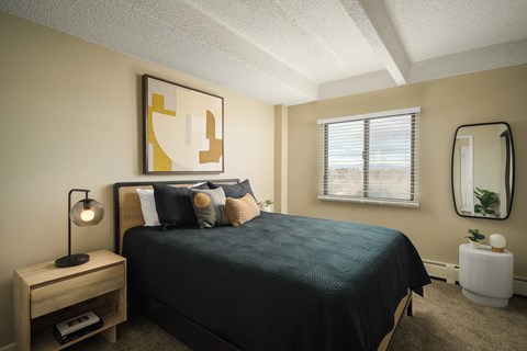 A bedroom with a bed, nightstand, and a painting on the wall.