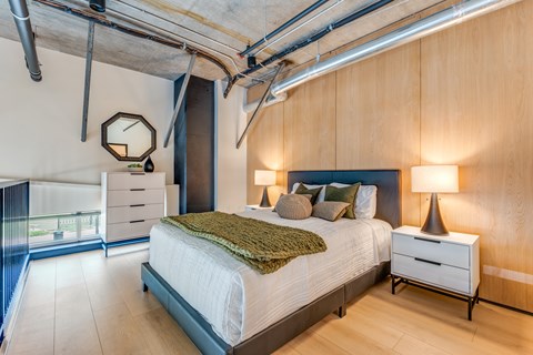 A bedroom with a bed, nightstand, and a window with a view of a balcony.