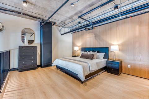 A bedroom with a bed, nightstands, and a wooden floor.