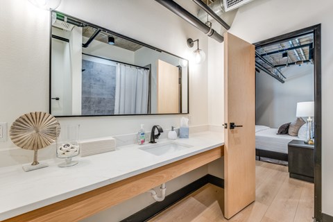 A bathroom with a sink, mirror, and a fan.
