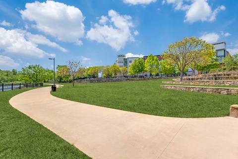 A park with a paved pathway and a grassy area.
