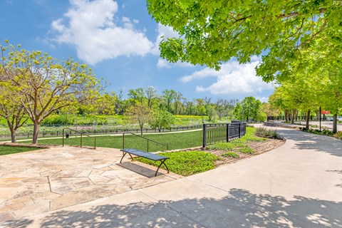 A park with a bench and a fence.