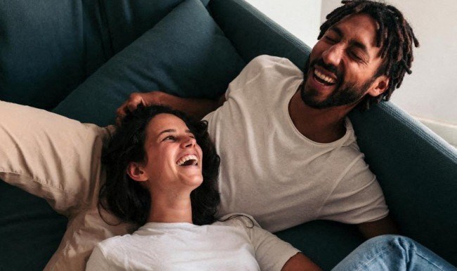 a man and a woman laughing on a couch