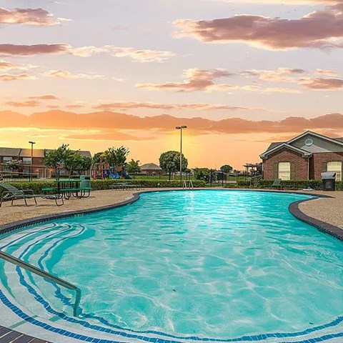 A large swimming pool with a sunset in the background.