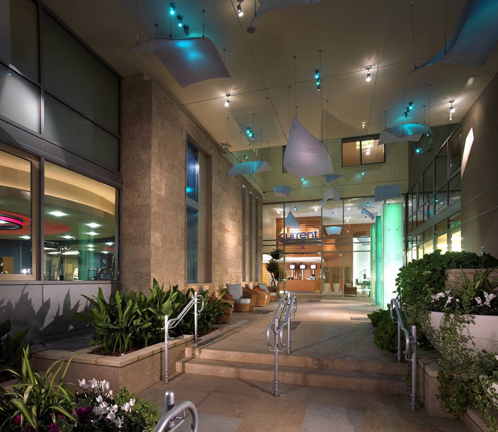 the lobby of an office building at night with stairs and plants