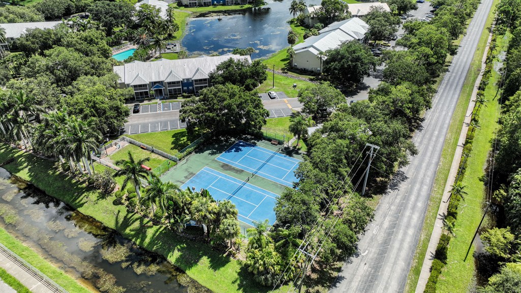 an aerial view of a tennis court and a house on a street