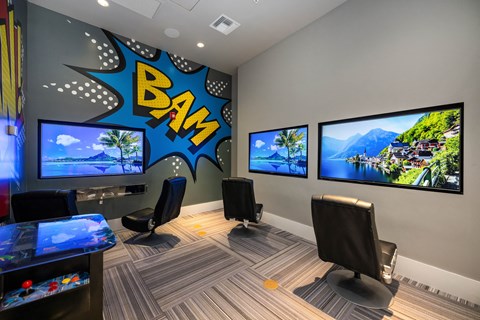 a large gaming room with three monitors and a boom sign