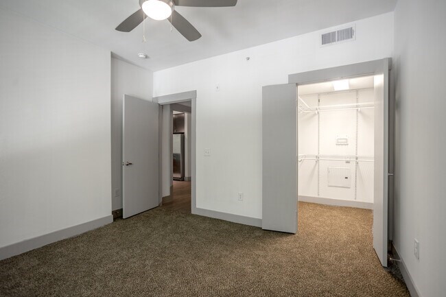 A room with a carpet floor and a ceiling fan.