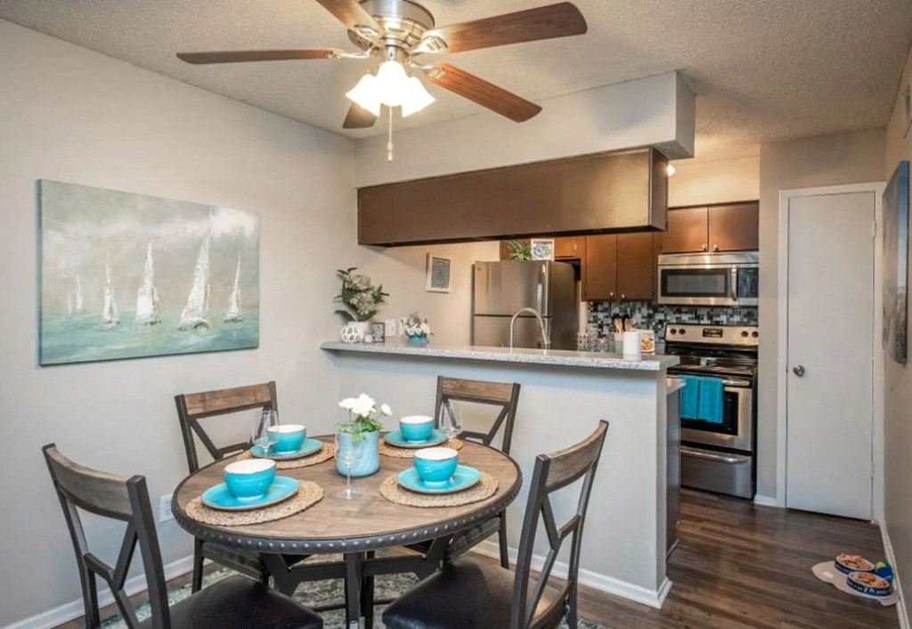 a dining area with a table and chairs and a kitchen in the background