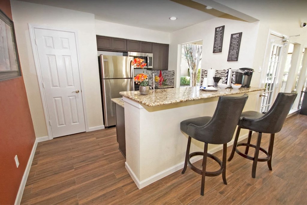 a kitchen with a breakfast bar and a stainless steel refrigerator