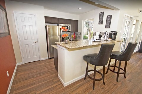 a kitchen with a bar and a stainless steel refrigerator