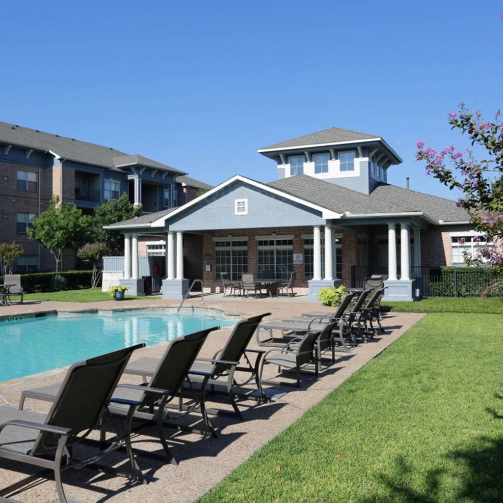 a pool with chairs in front of a building