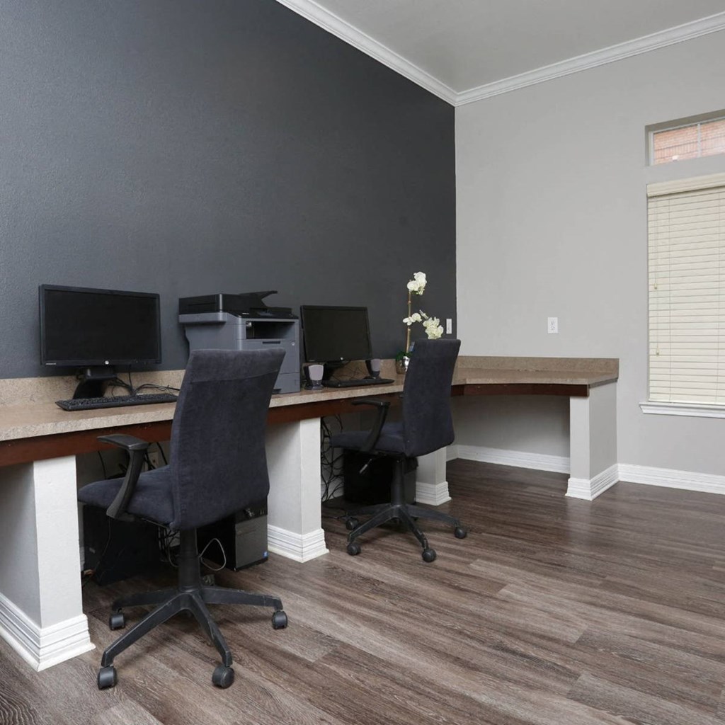 two desks with computers and chairs in a room with wood floors