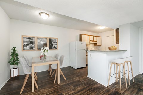 A kitchen with a white refrigerator and a dining table with chairs.