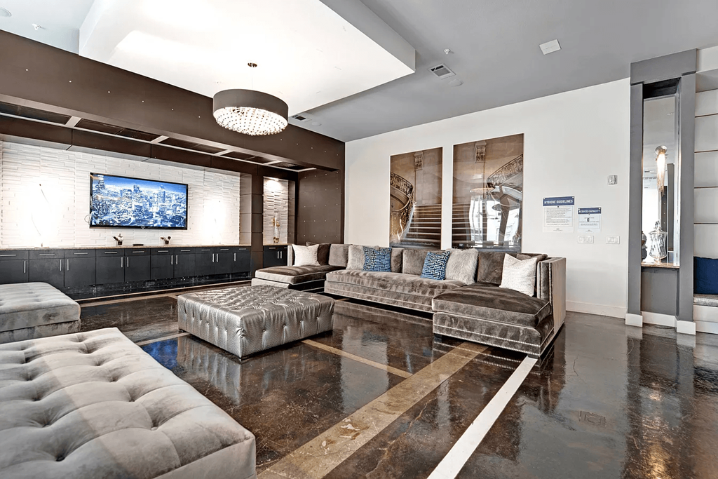 A modern living room with a grey sofa and a television on the wall.