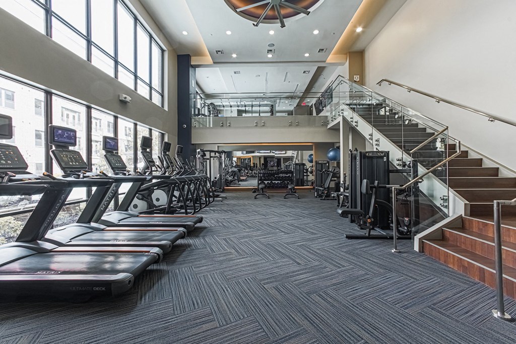 A gym with treadmills, elliptical machines, and a staircase.