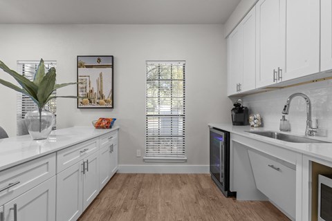 A kitchen with white cabinets and a wooden floor.