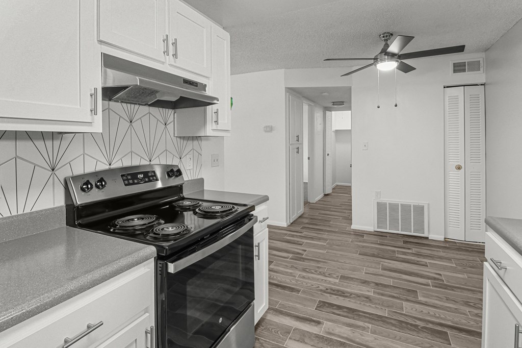 an empty kitchen with white cabinets and a black stove