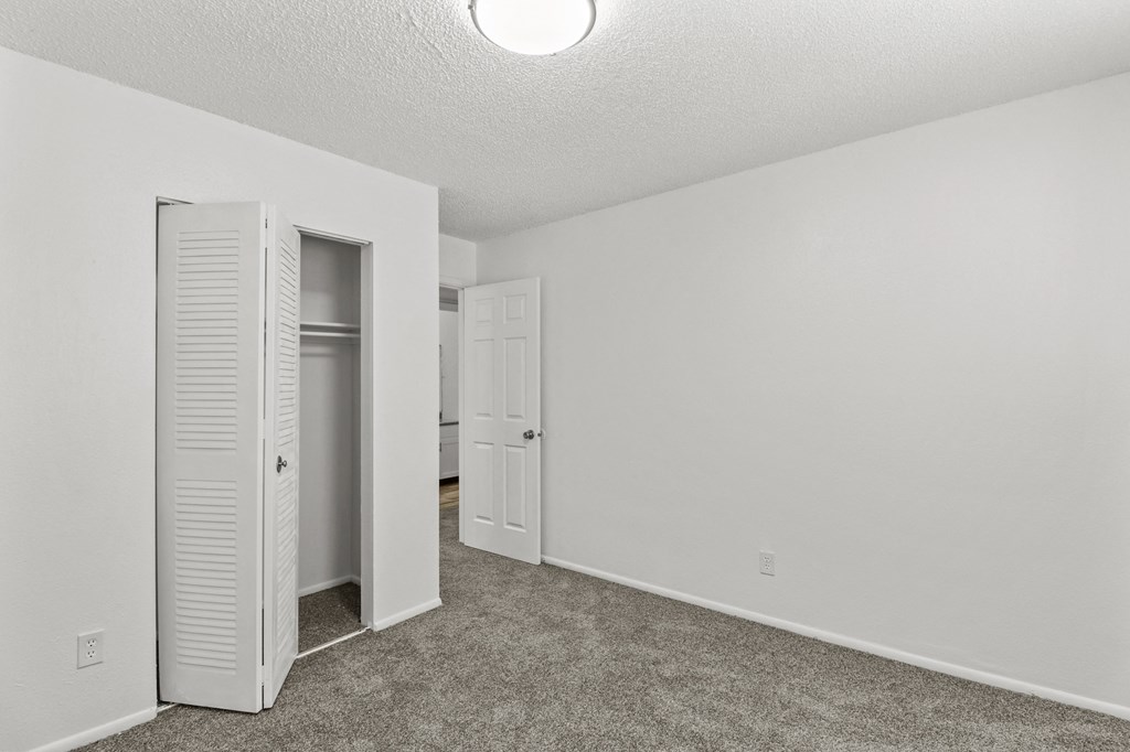 an empty room with a closet and an open door