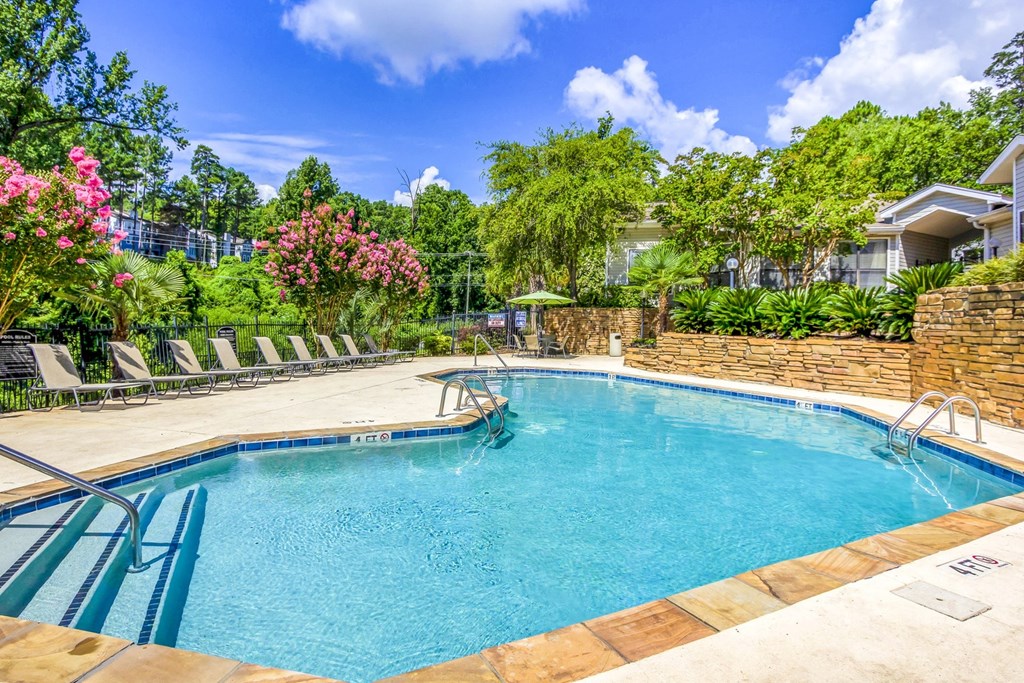 a swimming pool with chairs and a building in the background