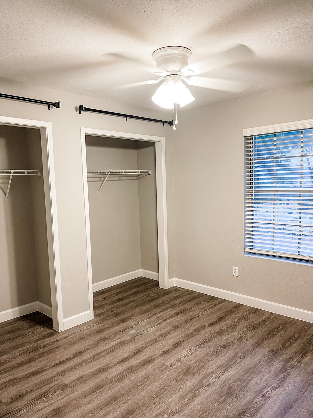 an empty bedroom with a closet and a ceiling fan with wood flooring