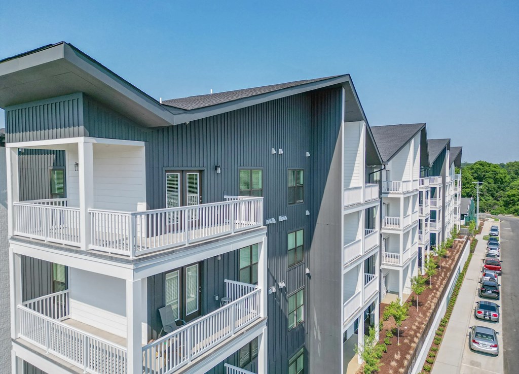 A modern apartment complex with balconies and a parking lot in front.