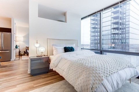 A bedroom with a large bed and a view of a building outside the window.